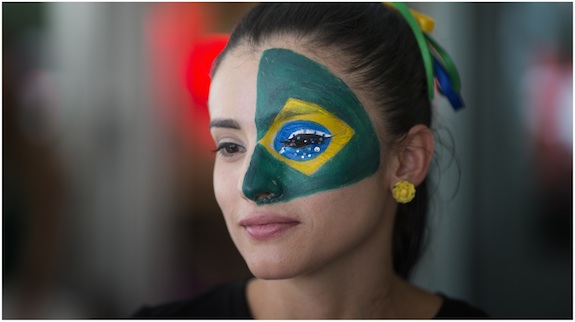 Soccer fan Marcella Guevara, with her face painted, watches televised World Cup soccer action between Brazil and Croatia at the Kukaramakara cafe block party in Miami, Thursday, June 12, 2014.